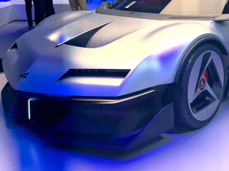 Face avant sculptée de l'Alpine A310 Vision, concept gris métal baigné de lumière bleue sur son stand parisien