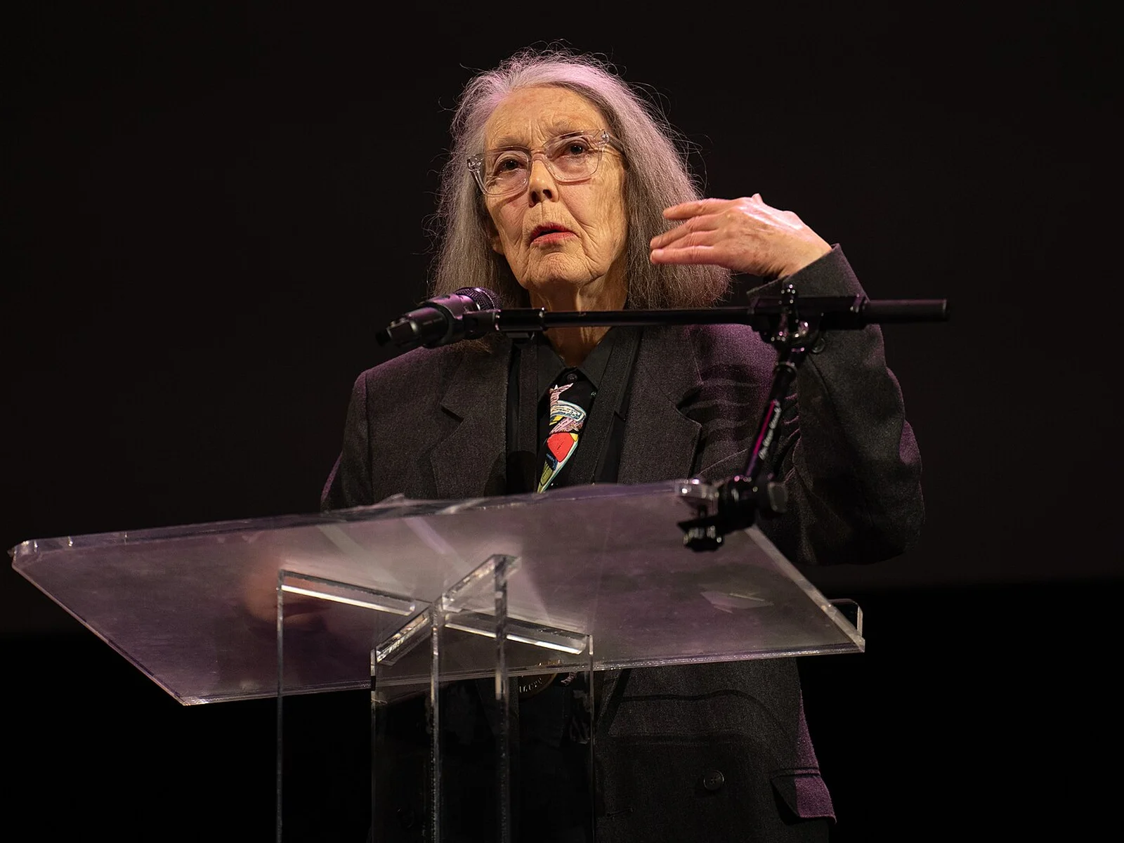 Anne Carson prenant la parole derrière un pupitre transparent lors d'une lecture aux National Book Awards 2024