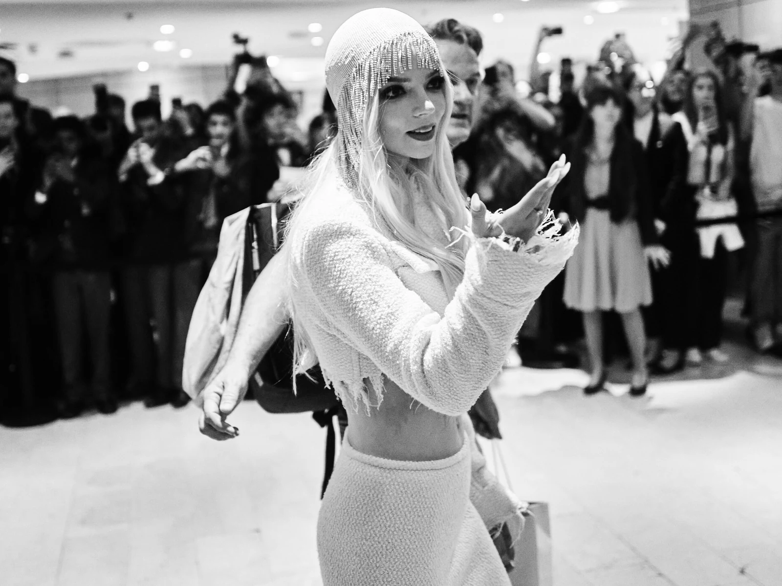 Anya Taylor-Joy en noir et blanc, bonnet de perles et tailleur bouclé, salue la foule au Festival de Cannes 2024