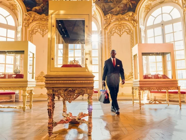 Assane Diop en costume sombre traverse une salle baroque dorée, scène de presse Lupin Partie 4 Netflix 2026