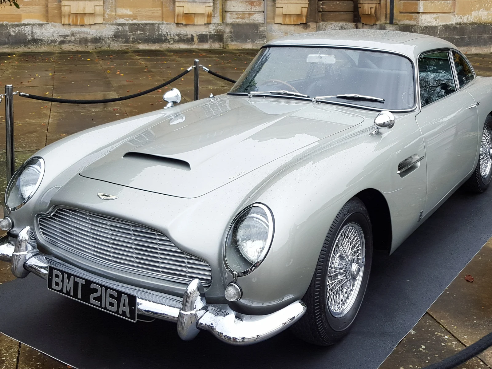 Aston Martin DB5 gris argent utilisée dans le film Skyfall, exposée derrière un cordon de velours à Blenheim Palace