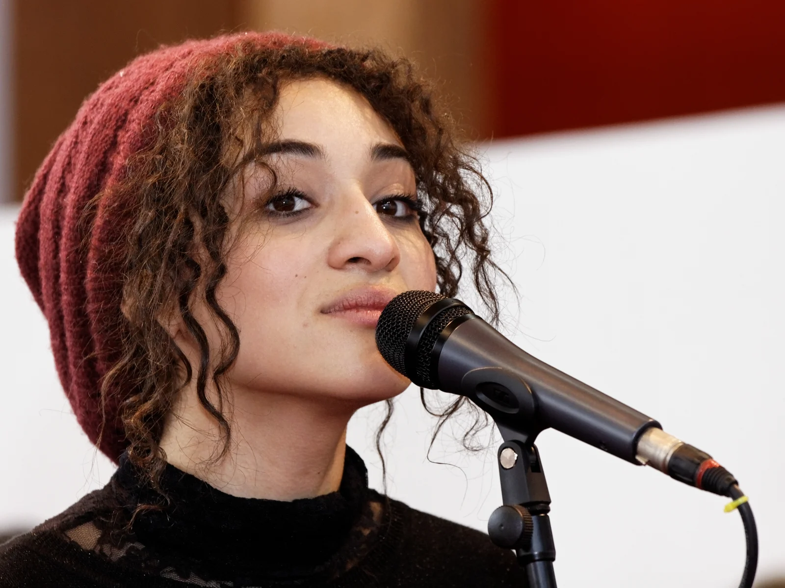 Camélia Jordana chantant au microphone, bonnet rouge, lors du Salon du livre de Paris en mars 2012