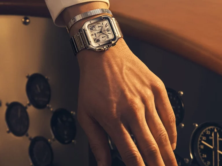 Montre Santos de Cartier chronographe au poignet, devant un tableau de bord d'avion vintage, campagne Cartier 2026