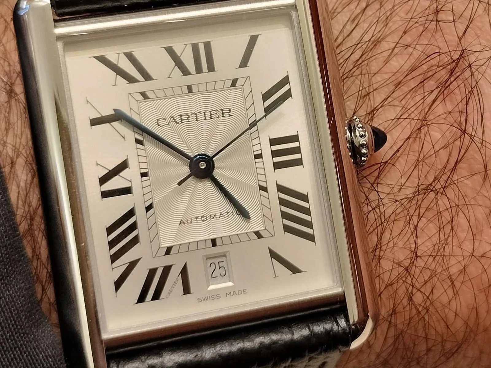 Gros plan sur une Cartier Tank Must XL automatique, cadran argenté à chiffres romains, au poignet d'un homme