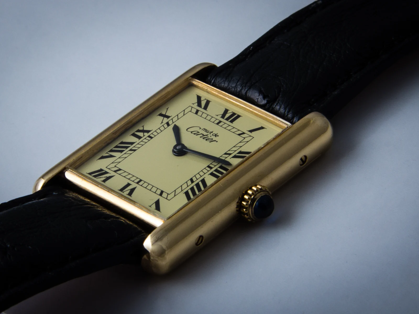Cartier Tank vintage en or jaune, cadran crème à chiffres romains et bracelet cuir noir, vue en gros plan