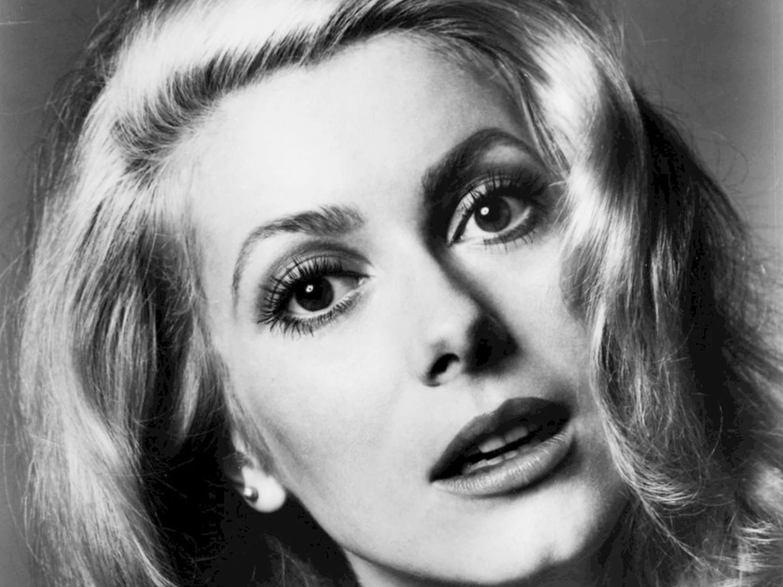 Portrait en noir et blanc de Catherine Deneuve en 1969, regard intense, lèvres entrouvertes, cheveux blonds en volume