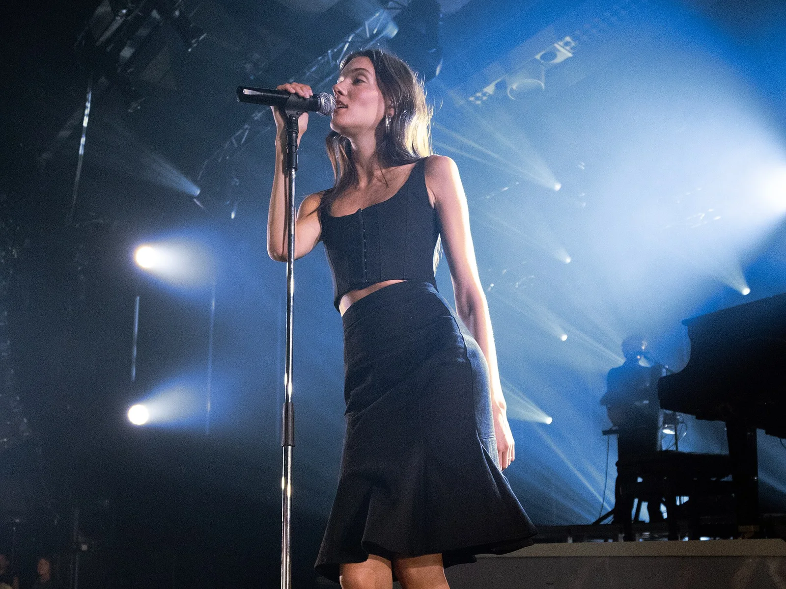Charlotte Cardin en top noir et jupe évasée chante au pied de micro sous une lumière bleue, Montreux Jazz Festival 2026