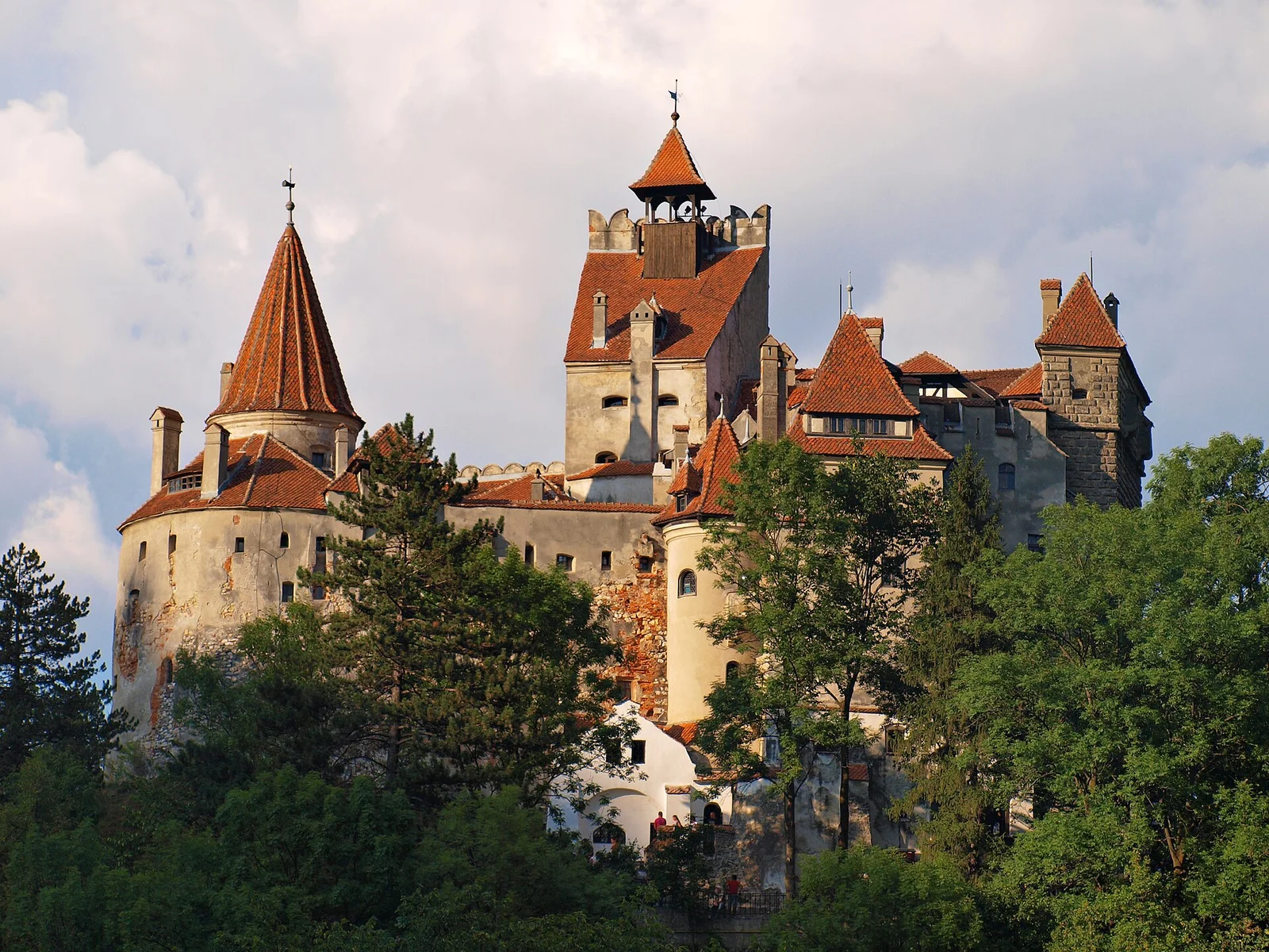 Le château de Bran en Transylvanie, tours aux toits de tuiles rouges dominant la forêt, lié à la légende de Dracula