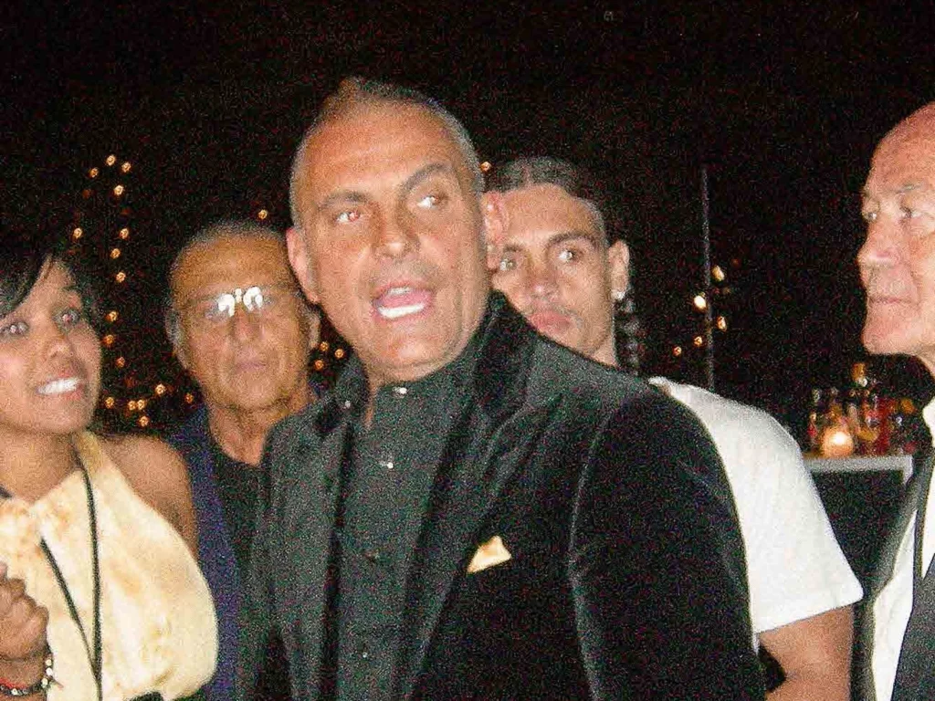 Christian Audigier en veste de velours noir lors d'une soirée à Los Angeles, entouré d'invités