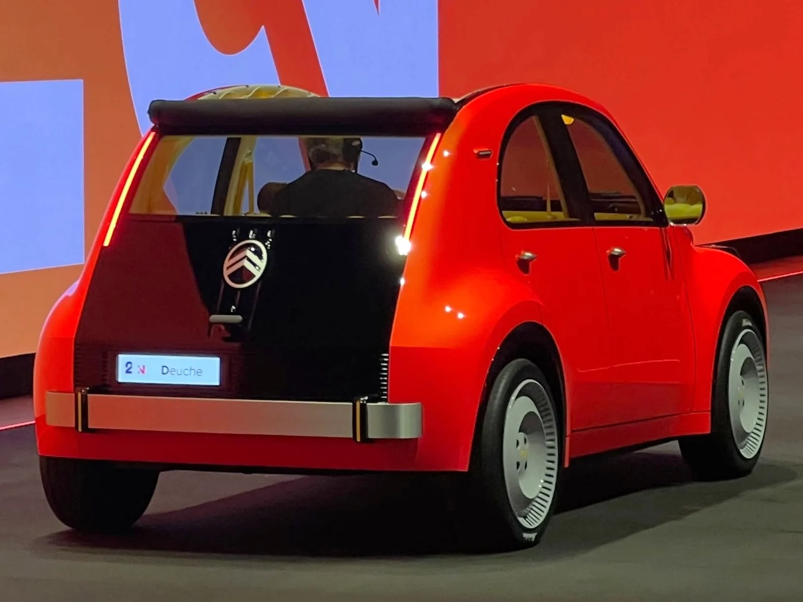 Vue arrière du concept Citroën 2CV électrique, carrosserie rouge et pare-chocs métal, sur le stand du Mondial 2026