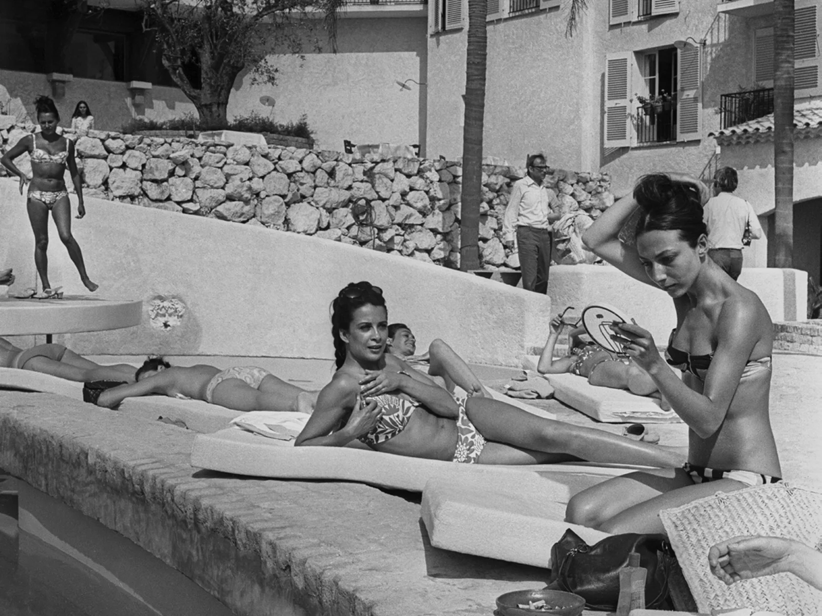 Baigneurs allongés au bord de la piscine de l'hôtel Byblos à Saint-Tropez, photographie d'archive en noir et blanc