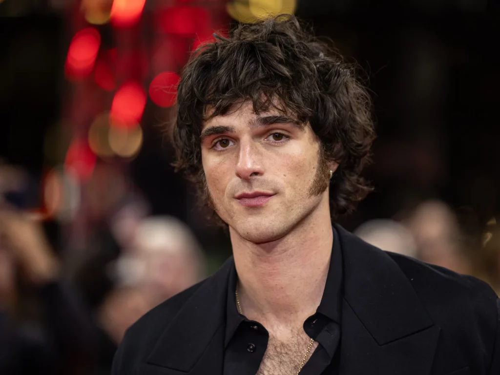 Portrait de Jacob Elordi en chemise noire sur le tapis rouge de la Berlinale 2025, regard direct, cheveux bouclés