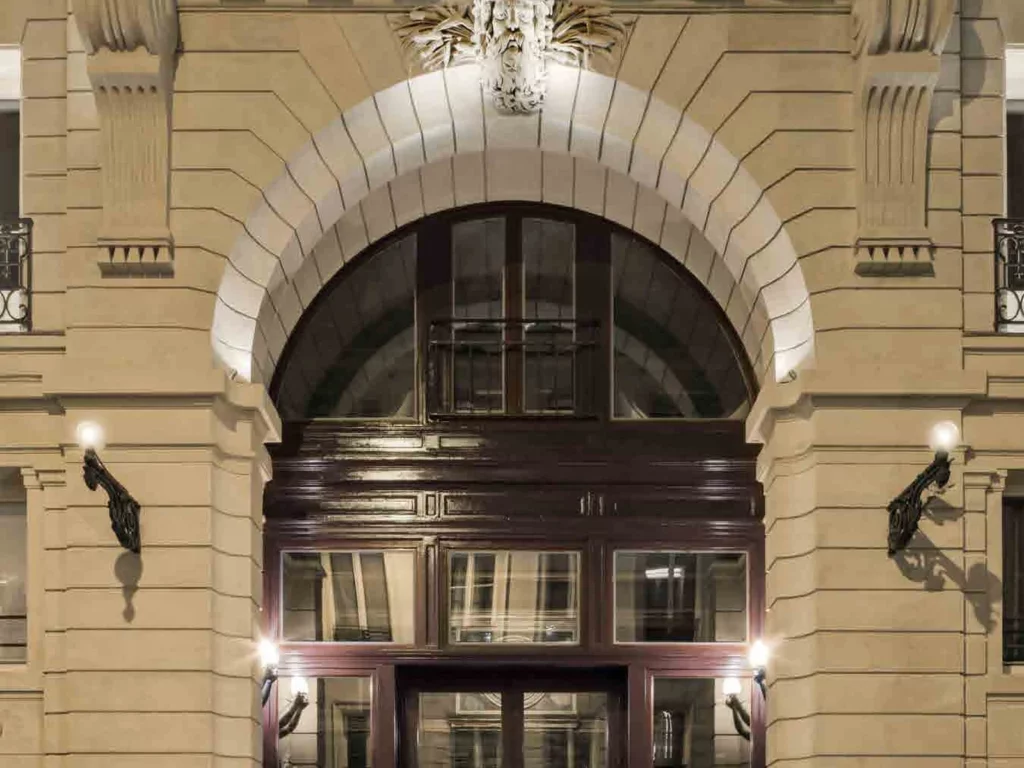 Façade en pierre des Bains à Paris, rue du Bourg-l'Abbé, avec son inscription Bains et sa porte vitrée éclairée