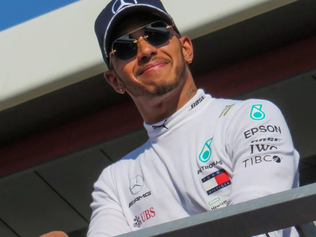 Lewis Hamilton souriant, lunettes de soleil et casquette, au Grand Prix de Grande-Bretagne à Silverstone en 2018