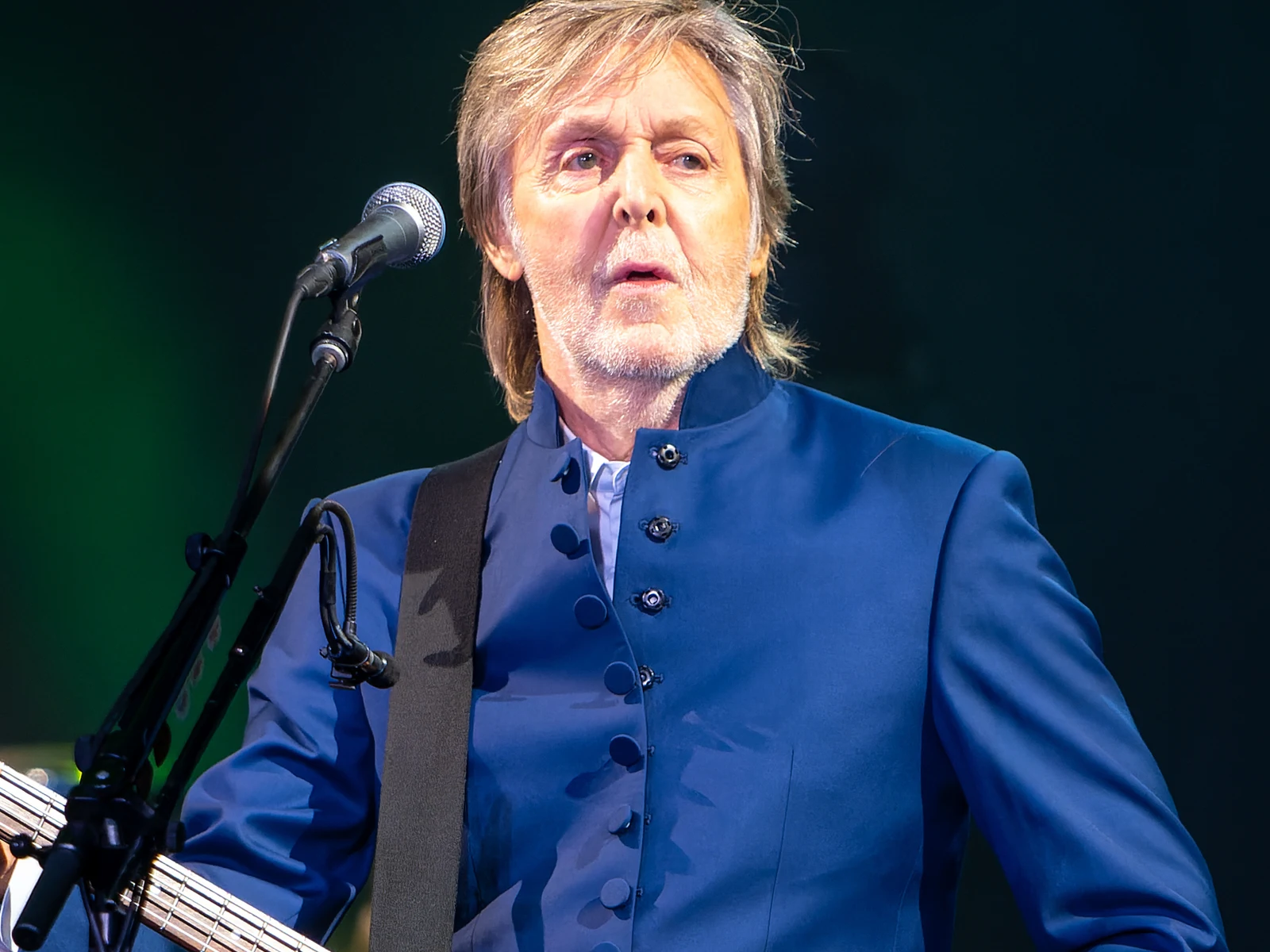 Paul McCartney en veste bleue à col montant devant son micro, basse à la main, sur scène à Glastonbury en 2022
