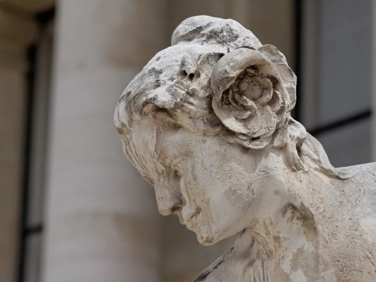 Sculpture de femme à la rose dans les cheveux, tête penchée, sur la façade du Petit Palais à Paris