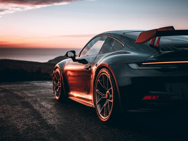 Porsche 911 GT3 thermique en lumière rasante au coucher du soleil, reflets cuivrés sur la carrosserie, Beachy Head