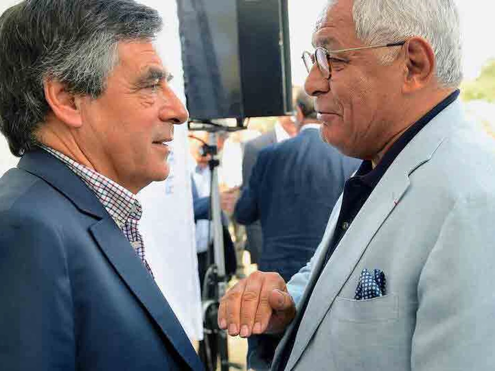 Robert Bourgi, cheveux blancs et veste claire, en conversation avec un homme politique en costume bleu