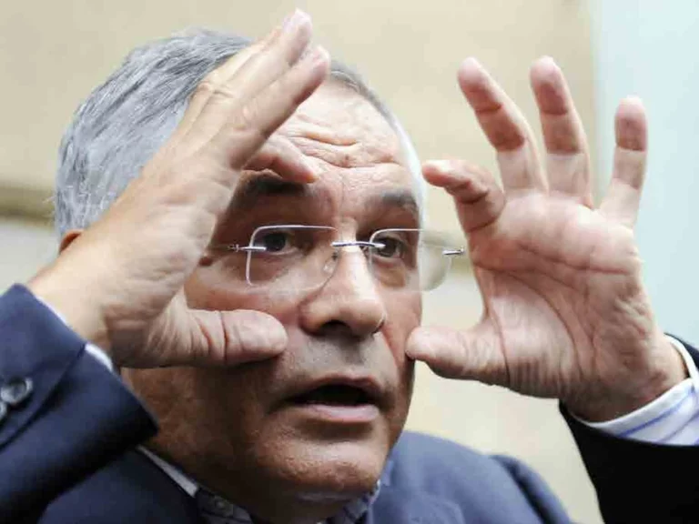 Robert Bourgi, lunettes et costume sombre, encadre son visage de ses deux mains lors d'une apparition publique