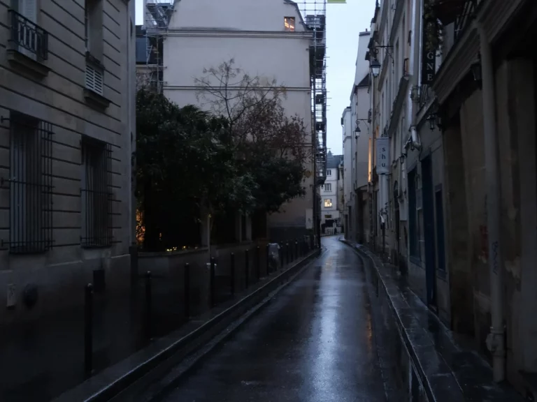 Rue Suger, Paris 6e, déserte et mouillée au crépuscule, entre façades de pierre sous une lumière bleutée