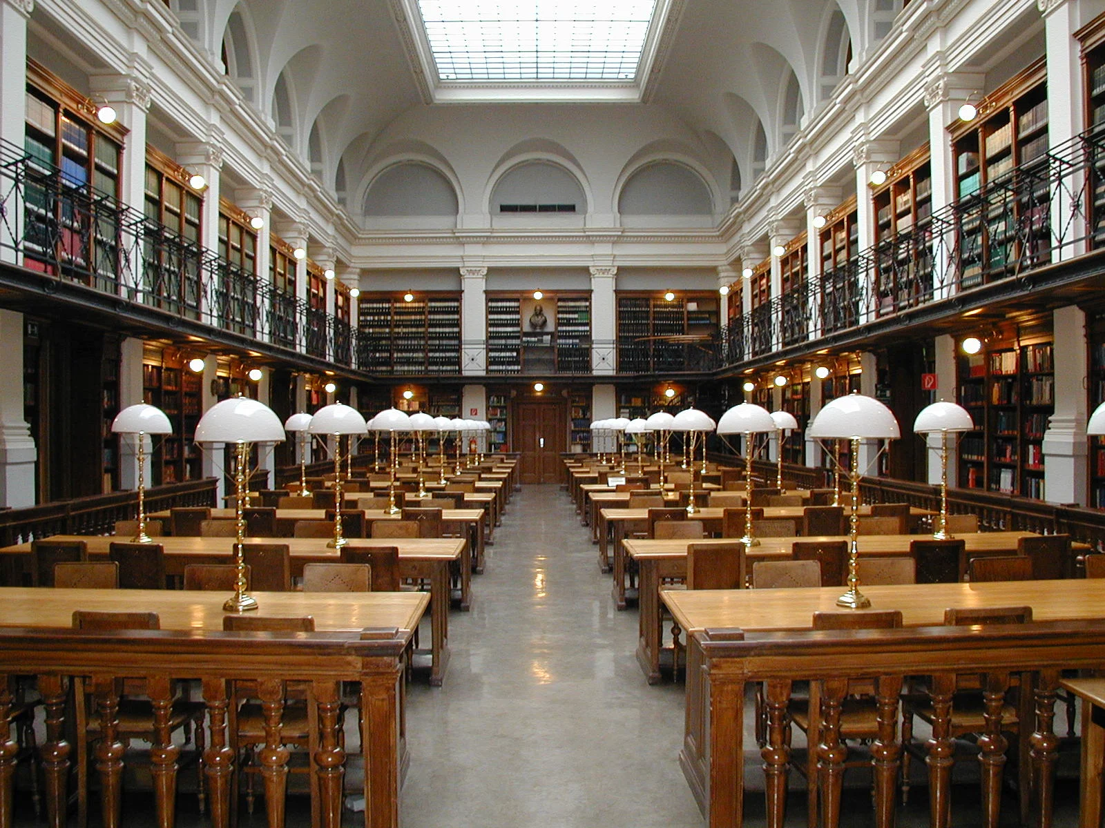 Longues tables de bois et lampes de laiton dans la salle de lecture de la bibliothèque universitaire de Graz, sans lecteur