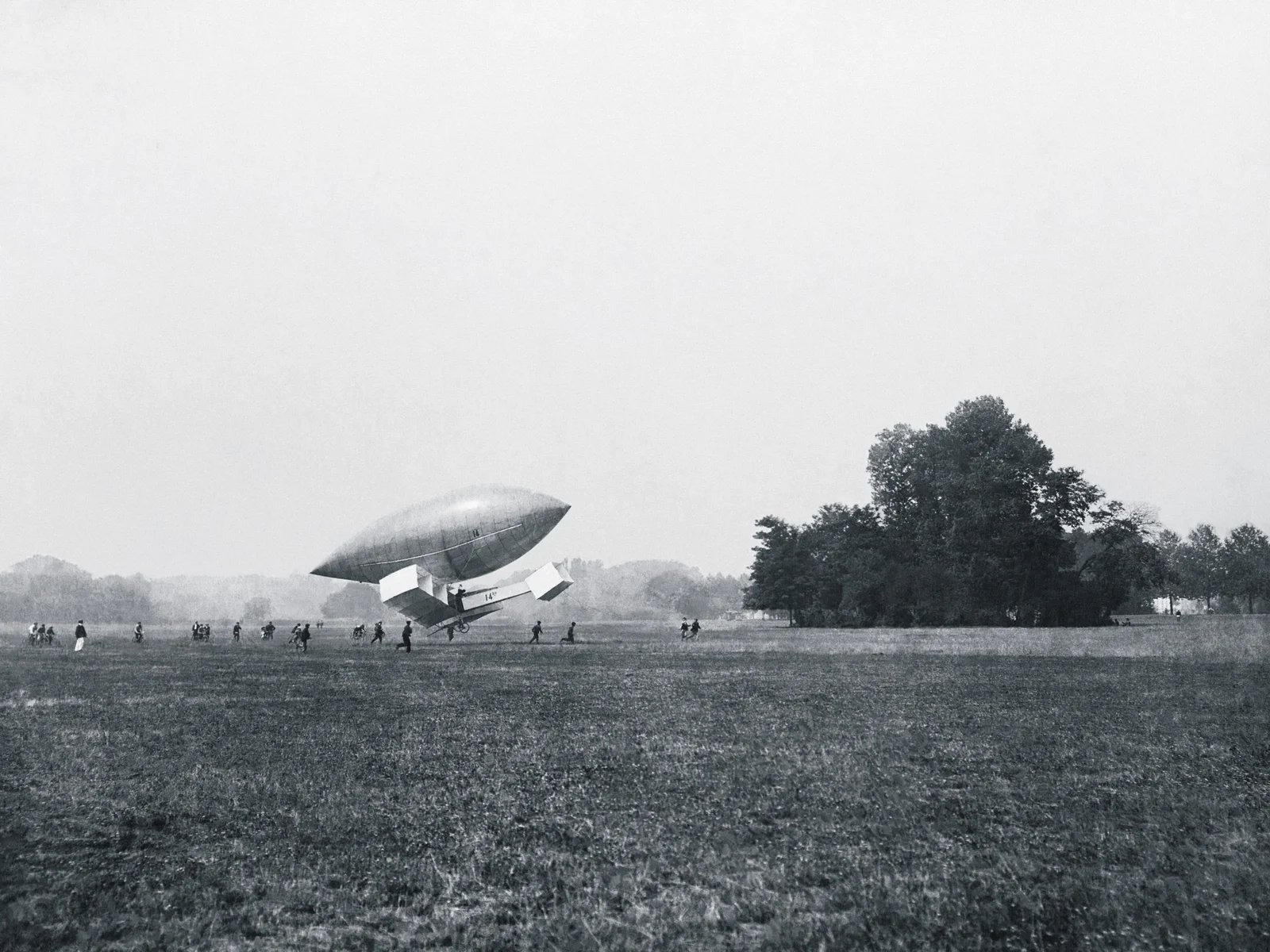 Le 14-bis d'Alberto Santos-Dumont sous un ballon de dirigeable sur le champ de Bagatelle, photographie de 1906